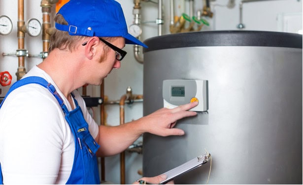 A photo of a person installing a heat pump hot water system.